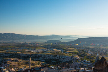 トルコ　カッパドキアのウチヒサール城から見える奇岩群と洞窟住居とギョレメ国立公園の空を飛ぶ熱気球