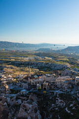 トルコ　カッパドキアのウチヒサール城から見える奇岩群と洞窟住居とギョレメ国立公園の空を飛ぶ熱気球