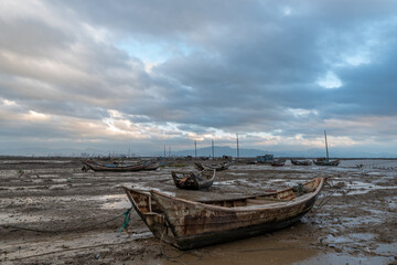 Fototapeta premium In the shallow area before sunrise in the morning, there are cloudy clouds and many fishing boats on the beach