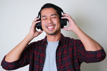 Young Asian man enjoying music using headset