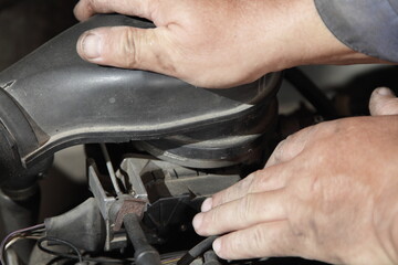 Old car engine air intake check - service man hands holding the air filter box on single injection fuel system unit closeup, motor repair service
