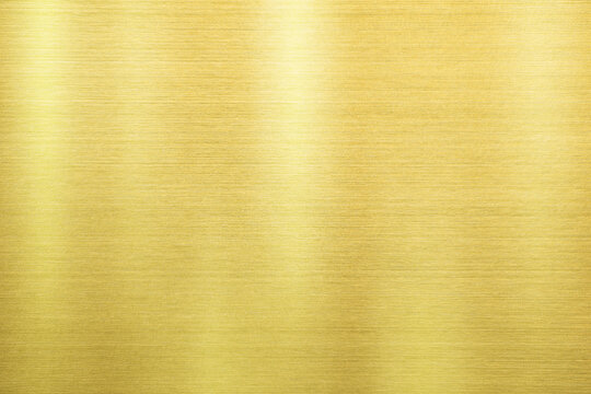 Shiny gold polished metal background texture of brushed stainless steel plate with the reflection of light.