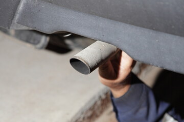 Test the exhaust system of the used car - a man's hand checks the exhaust silencer pipe clamp...