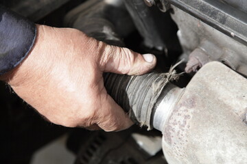 Air heating for an automobile engine intake in winter - a man's hand puts a nozzle on the exhaust manifold heat shield closeup, seasonal vehicle maintenance service
