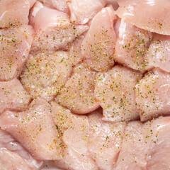 Raw chicken fillet chunks with spices top view, background