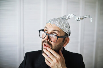 Bearded funny man in a cap of aluminum foil. Concept art phobias.Conspiracy theory. Conspiracy....