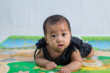 6 months old baby girl learning to crawl on the floor. Asian cute baby girl crawling on the floor with positive expression. 