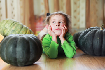 Fototapeta premium Little child choose a pumpkin at autumn. Child sitting on giant pumpkin. Pumpkin is traditional vegetable used on American holidays - Halloween and Thanksgiving Day.