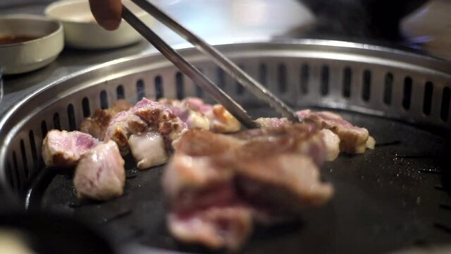 한국 정통 삼겹살을 숯불에 맛있게 굽는 모습 상추와 쌈장 마늘등에 싸서 먹는다