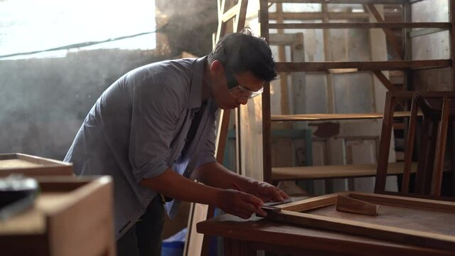asian carpenter wearing Safety Glasses measure distance with a pencil and a corner ruler wood  in workshop .craftsman Mark point to window or furniture