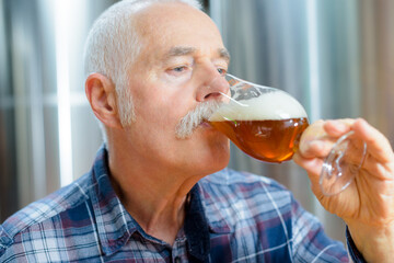 elderly man drinking beer tank on background