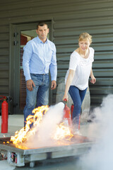 a woman demonstrating how to use a fire extinguisher