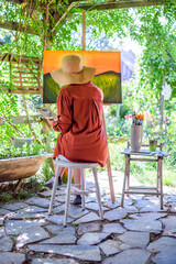 Young female artist working on her art canvas painting outdoors in her garden. Mindfulness, art...