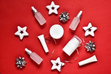 Christmas cosmetics products. Idea for winter shopping, present. White cosmetic bottles containers with gift box on a red background. Moisturizing skincare product. Holiday concept. Flat lay, top view