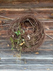 A wreath of rusty wire with green plants hanging on an old wooden wall