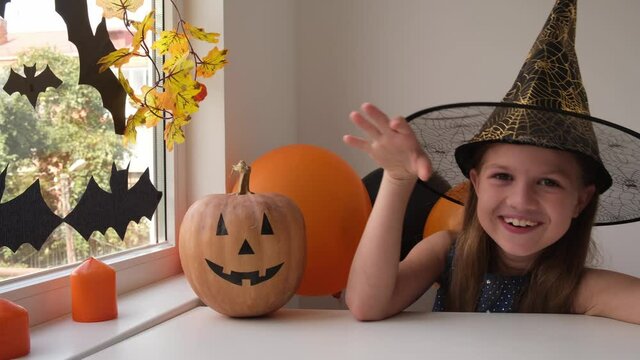 Laughing happy little girl in witch costume preparing for Halloween at home. Looking at camera, saying boo. Holiday decoration concept