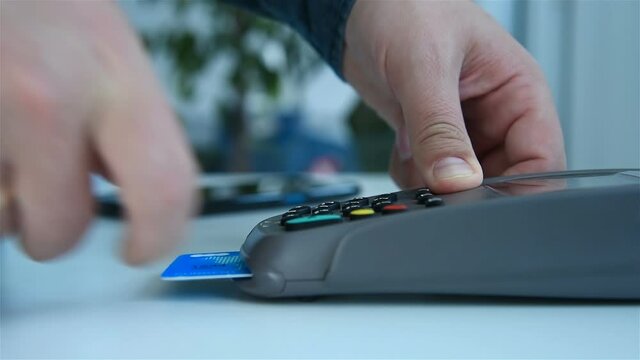 Hand Inserts Credit Card Into Terminal And Enters Password For Payment. Electronic Money And Shopping Concept.  Slow Motion Effect. Close Up