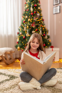 Little Girl Reading Giant Book By The Christmas Tree