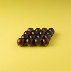 Grapes arranged in a square. Yellow minimalist autumn composition.