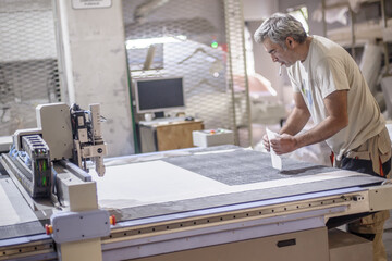 Technician works on CNC digital cutter machine for cutting textile