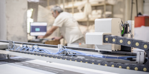 Technician works on CNC digital cutter machine for cutting textile