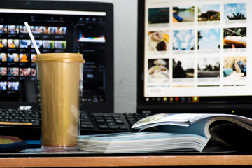 A golden mug sits on the table and a book is placed beside it. And with the background, it's a notebook and a computer monitor.