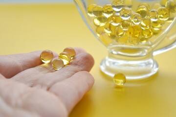 Vitamin oil capsules in hand close up and capsules in a glass healthy lifestyle