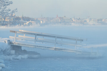 Ice covered floating pontoon loading dock with  by the icy Baltic sea in Helsinki, Finland.