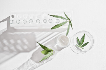 cannabis face cream and hemp leaves in laboratory . petri dishes and glassware on lab table....