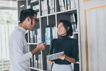 Obraz premium Asian business team who consulting at the office with daylight from window and blur garden background.
