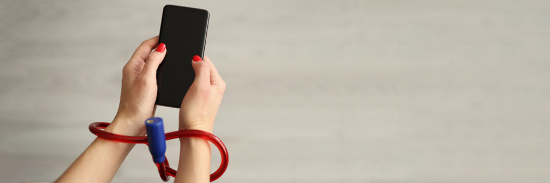 Woman with tied hands holding mobile phone closeup