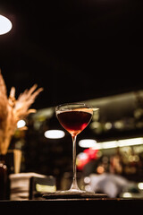 A classic Manhattan cocktail garnished with an orange zest in a beautiful glass at the bar