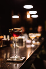 A classic Manhattan cocktail garnished with an orange zest in a beautiful glass at the bar