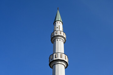 Minaret and mosque against blue sky.  