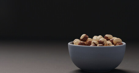 roasted hazelnuts in blue bowl on black background