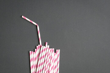 Glass with straw made up of paper straws on black background. Party or no plastic concept.
