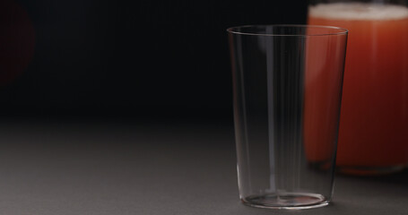 grapefruit juice in glass bottle and tumbler glass on black background