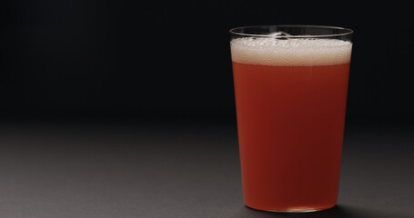 grapefruit juice in tumbler glass on black background