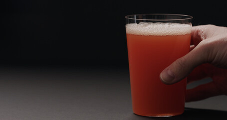 man hand take grapefruit juice in tumbler glass on black background