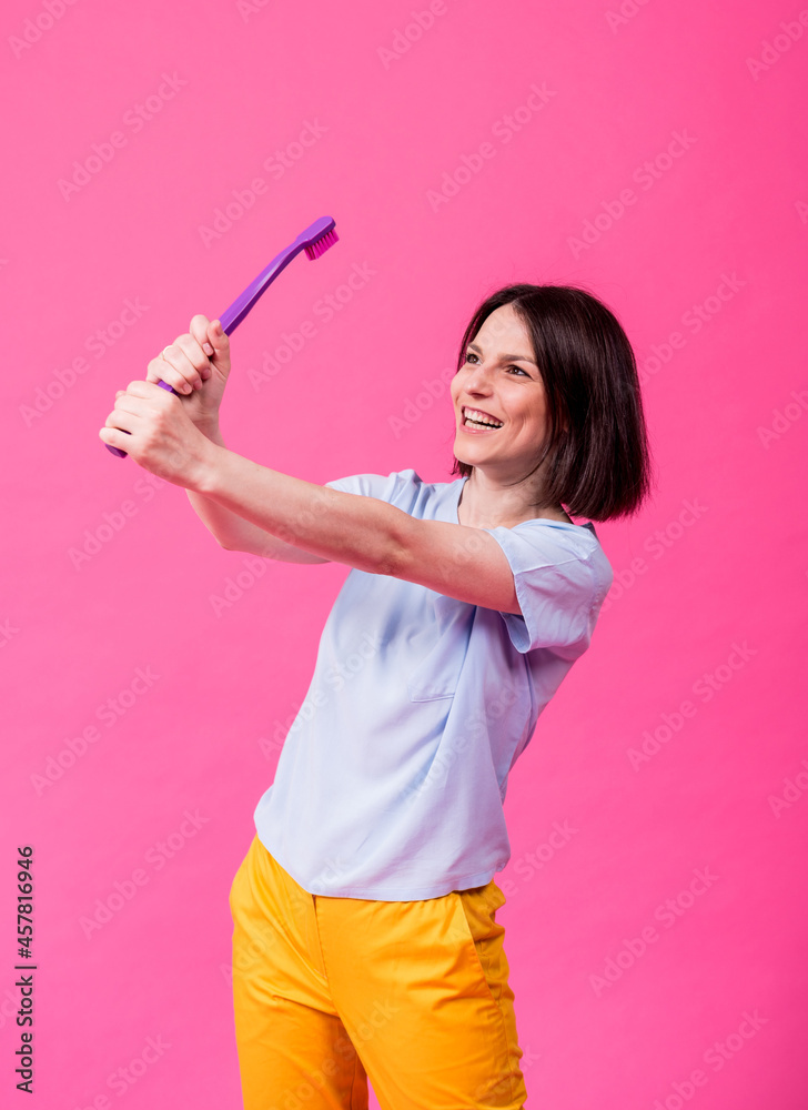 Wall mural Beautiful happy young woman with big toothbrush on blank pink background