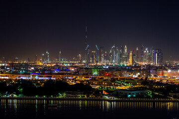 Fototapeta na wymiar Dubai, UAE – January 16, 2016 – City skyline seen from Deira district in a beautiful, peaceful night. In the foreground, the ships in Port Saeed docks