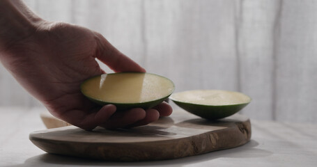Obraz na płótnie Canvas man cut green mango on olive wood board