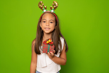 Happy little smiling girl in santa hat with christmas gift box.