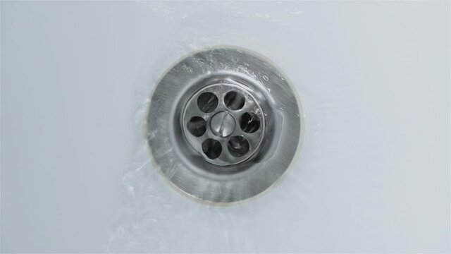 Water is poured into the bathtub and drained into the drain hole, top view. 