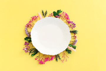 Top view image of pink, purple and green flowers composition over pastel yellow background .Flat lay