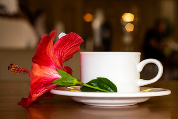 A cup of tea with a red flower on the table.