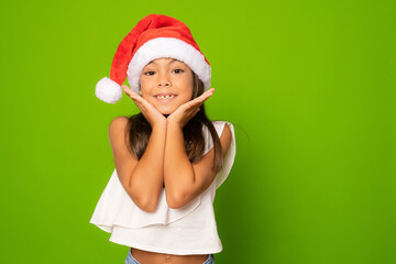 Happy little girl in santa hat isolated over green background.