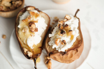 top view of sweet pears stuffed with cream cheese and nuts. grilled fruits as vegetarian dessert. white rustic table. honey topping.