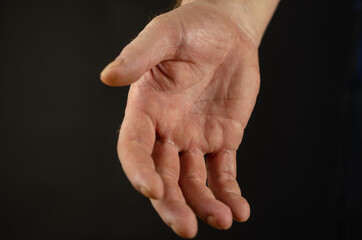 Close-up of a man's hand outstretched for a handshake. Open palm against a black background. Selective focus.