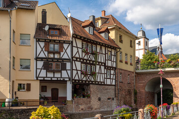 Half-timbered house and other buildings in the old town of Neckarsteinach in Hesse, Germany with baroque church in the background - obrazy, fototapety, plakaty